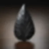 A beautifully crafted arrowhead made from obsidian, showcasing intricate flaking patterns.