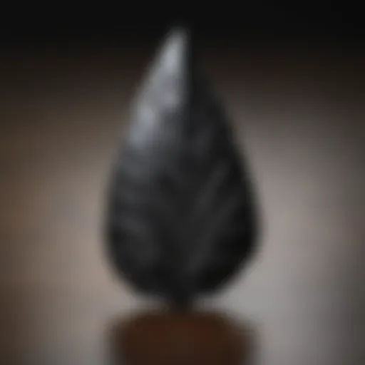 A beautifully crafted arrowhead made from obsidian, showcasing intricate flaking patterns.
